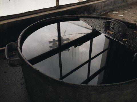 Reflection of light in an old grungy oil barrel in an abandoned garage