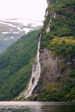 Cottages next to waterfall situated at a fjord