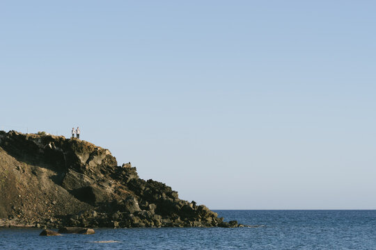 Young couple standing on the cliff beside sea