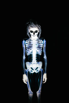 Spooky portrait of woman in skeleton costume and halloween make up on black background