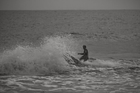 Black and white image of a surfer riding a wave.