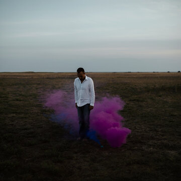Man standing in a purple smoke in nature