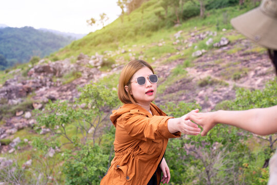 Tourist Asian Women Getting Help To Friend Climb A Rock,Helping Hands,Overcoming Obstacle Concept