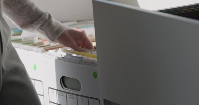 Close up of a womans hands going through boxes of paperwork and filing it away
