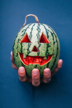 colorful Halloween watermelon in hand on a blue background