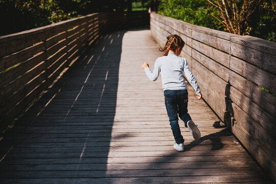 Girl running for fun on a wooden bridge in a park