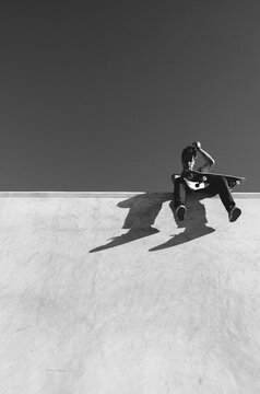 Skateboarder resting on half pipe wall