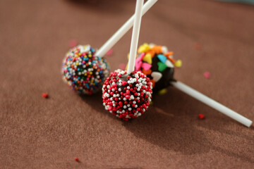 Festive chocolate cake pops with candy sprinkles close-up on the table