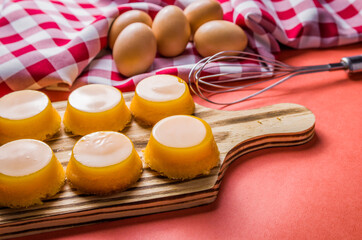 Delicious Quindins on wooden board, traditional Brazilian dessert made with egg yolk, sugar and coconut.