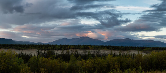 Naklejka na ściany i meble Beautiful Panoramic View of Canadian Mountain Landscape during a colorful cloudy sunset. Located near Whitehorse, Yukon, Canada. Nature Background Panorama