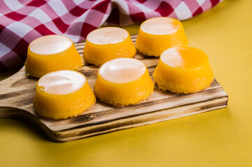 Delicious Quindins on wooden board, traditional Brazilian dessert made with egg yolk, sugar and coconut.