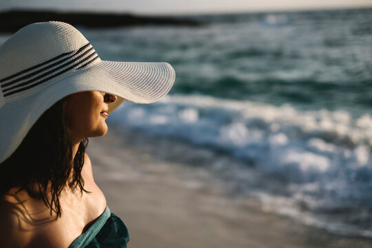 Beautiful young woman with hat on the beach
