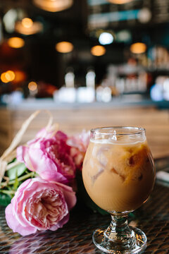 Fancy Iced Coffee with cream in a Glass beside pink flowers