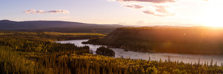 Beautiful View of Scenic Valley from Above alongside Winding River, Forest and Mountains at Sunset. Aerial. Taken near Klondike Highway, Yukon, Canada.
