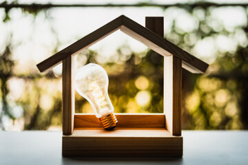 Light bulb with wood house on the table, a symbol for construction, Creative light bulb idea, power energy or business idea concept ecology, loan, mortgage, property or home. © sommart