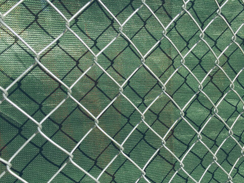Detail of chain link fence and green fabric at construction site