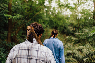 Men walking in the forest with axes on the shoulder