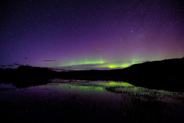 Northern lights, aurora borealis, over the lake in the Northern Canadian Nature at Night. Taken at Fish Lake near Whitehorse, Yukon, Canada.