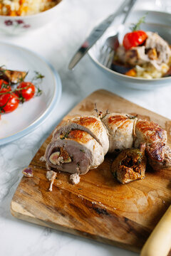 Cooked pork fillet,stuffed with figs and shallots on cutting board.