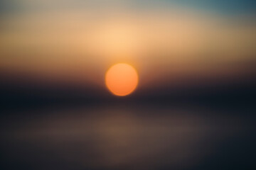 Sunset over calm ocean, blurred focus