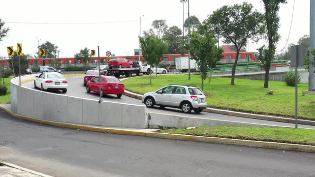 Autom&oacute;viles incorpor&aacute;ndose a una vialidad principal, desde un tr&eacute;bol, con el Metro, sistema de transporte p&uacute;blico, en el fondo.