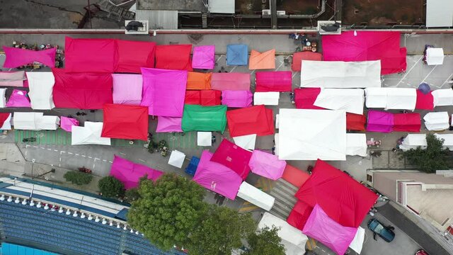 Vista a&eacute;rea cenital, el drone descendiendo lentamente, sobre los coloridos puestos de lona de un mercado callejero de la Ciudad de M&eacute;xico