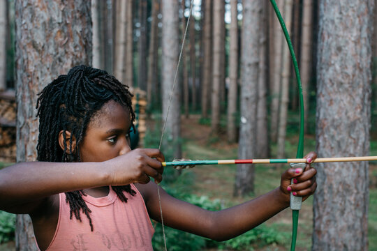 Black girl with bow and arrow aiming at target