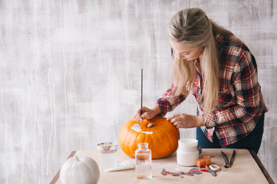 Woman painting on pumpkin using decoupage technique