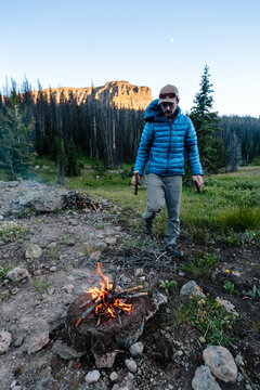 Man gathering wood and assembling small fire for camping