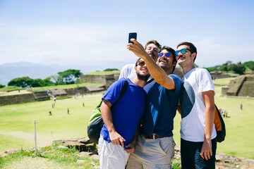 Group of happy friends taking a self portrait of them in some ruins landmark while their vacation travel