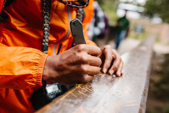 A man carving his name into a bridge in the woods