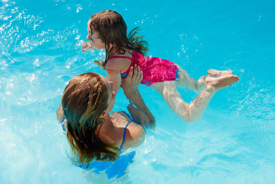 Mom and daughter having fun in pool learning to swim