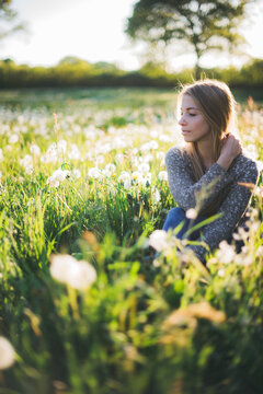 a girl is sitting in a dandelion meadow