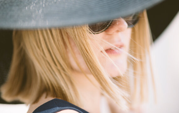 young blond woman with black hat and glasses