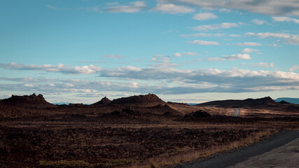 Fototapeta na wymiar Desertic road with mountains and rocks and cloudy sky iceland
