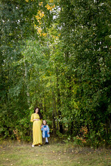 Fototapeta na wymiar Pregnant woman in yellow dress with her daughter in nature