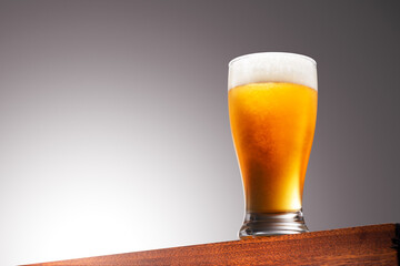 Close up photo of a Glass of beer on a Wooden Surface and Gradient Background