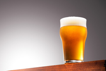 Close up photo of a Glass of beer on a Wooden Surface and Gradient Background