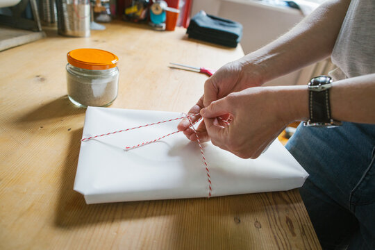 Close Up of Caucasian Woman Tying String on Parcel in Bright Dressmaking Atelier