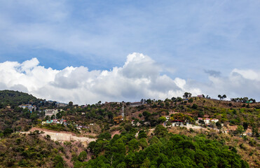Fototapeta na wymiar wide view of a mountain with residential properties shot from low angle and clouds in the blue sky