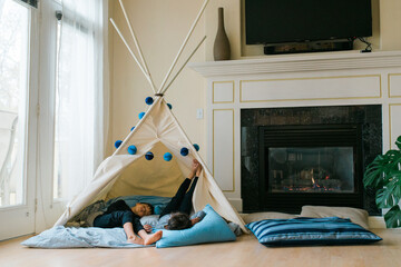 two young boys asleep in a teepee fort