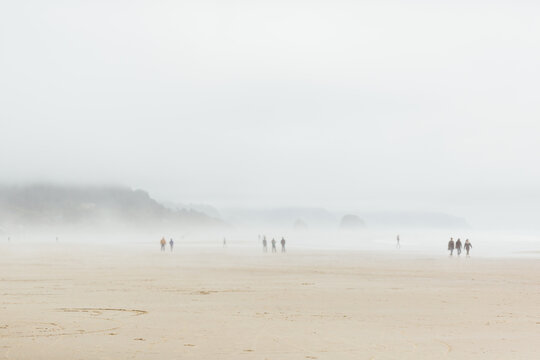 People walking on the beach in a foggy day