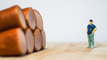 Miniature people : Close up fat man standing with sausages isolated on white background 