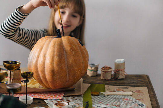 Happy Girl Decorating a Pumpkin for Halloween