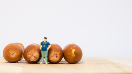 Obraz na płótnie Canvas Miniature people : Close up fat man standing with sausages isolated on white background 