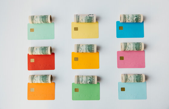 Colored credit cards with money rolls over them