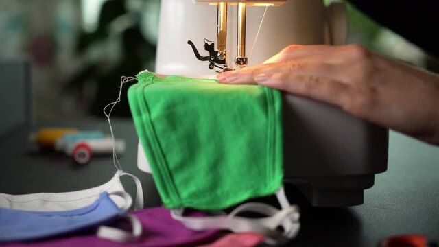A woman sewing protective medical face masks on a sewing machine.