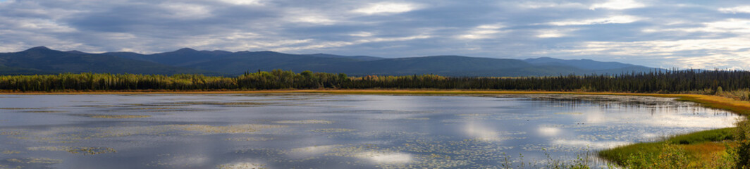 Beautiful Panoramic View of Gravel Lake near Klondike Hwy during a sunny and cloudy sunrise. Yukon, Canada. Nature Background Panorama