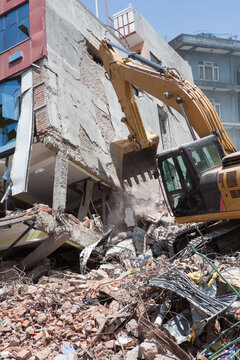 An excavator clearing debris of a fallen building after an earthquake.