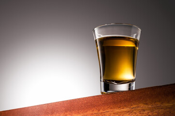 Close up photo of a Gold Tequila Glass Shot Wooden Surface and Gradient Background